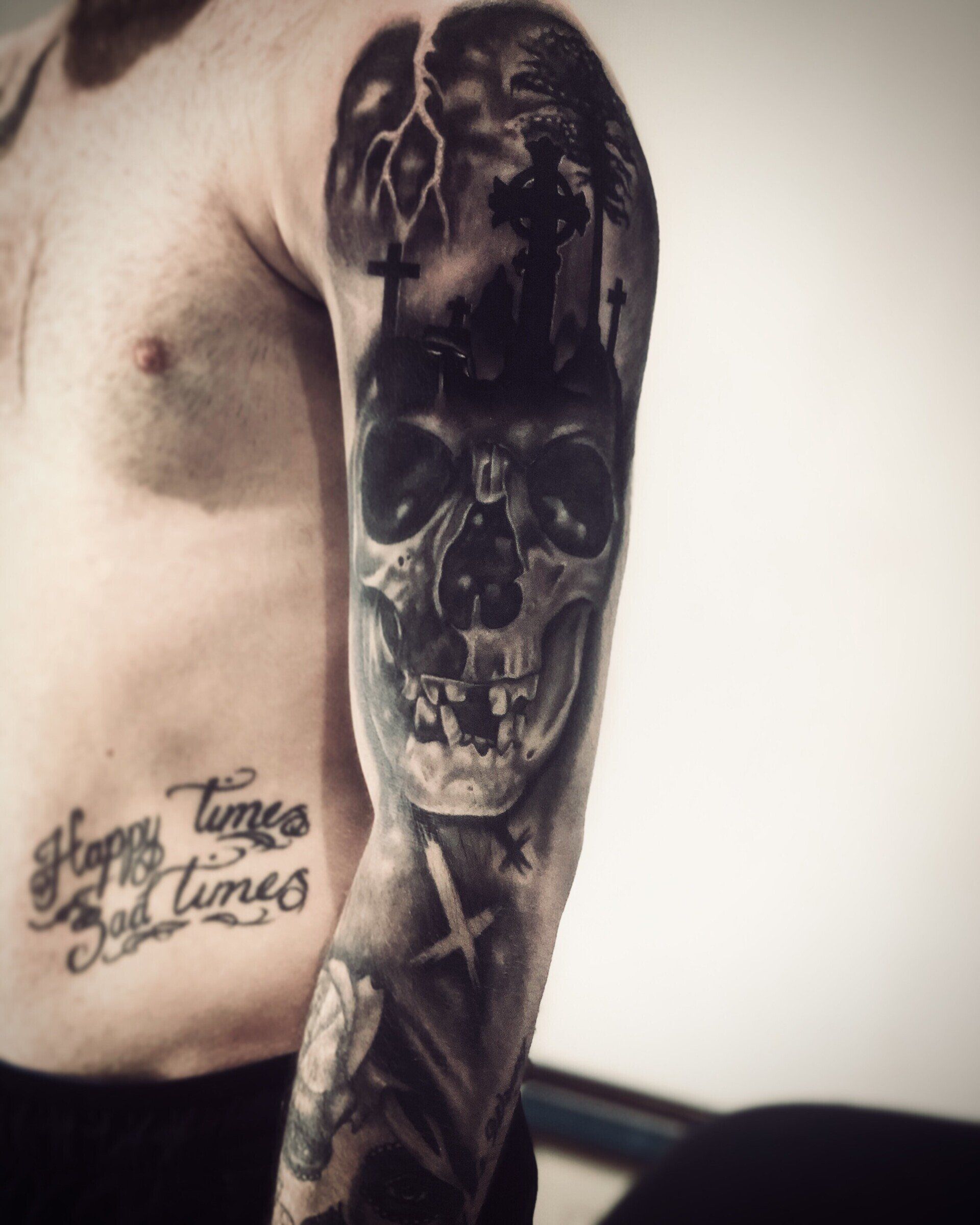 A man has a tattoo on his arm that says happy times bad times