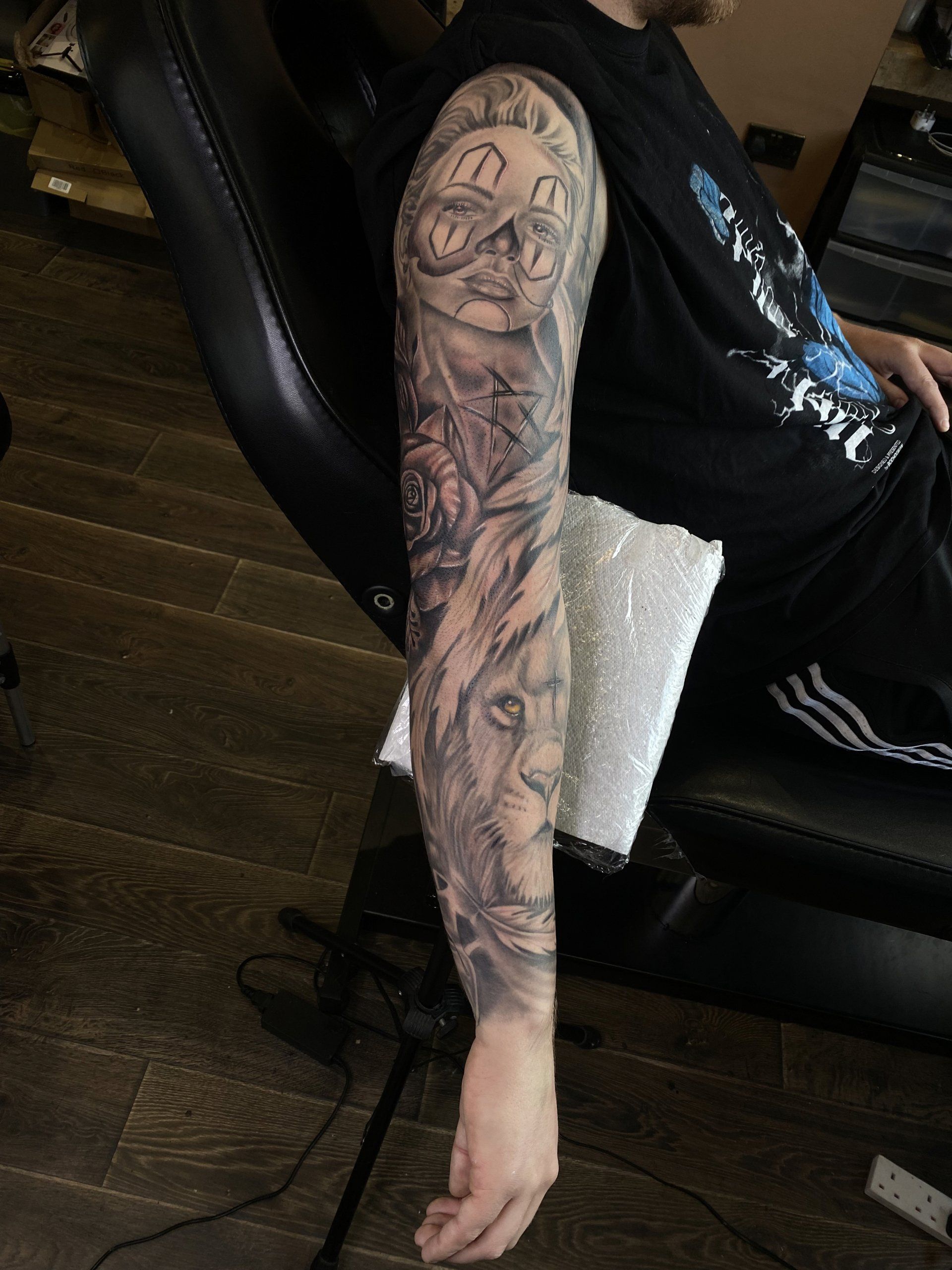 A man with a tattoo on his arm is sitting in a chair