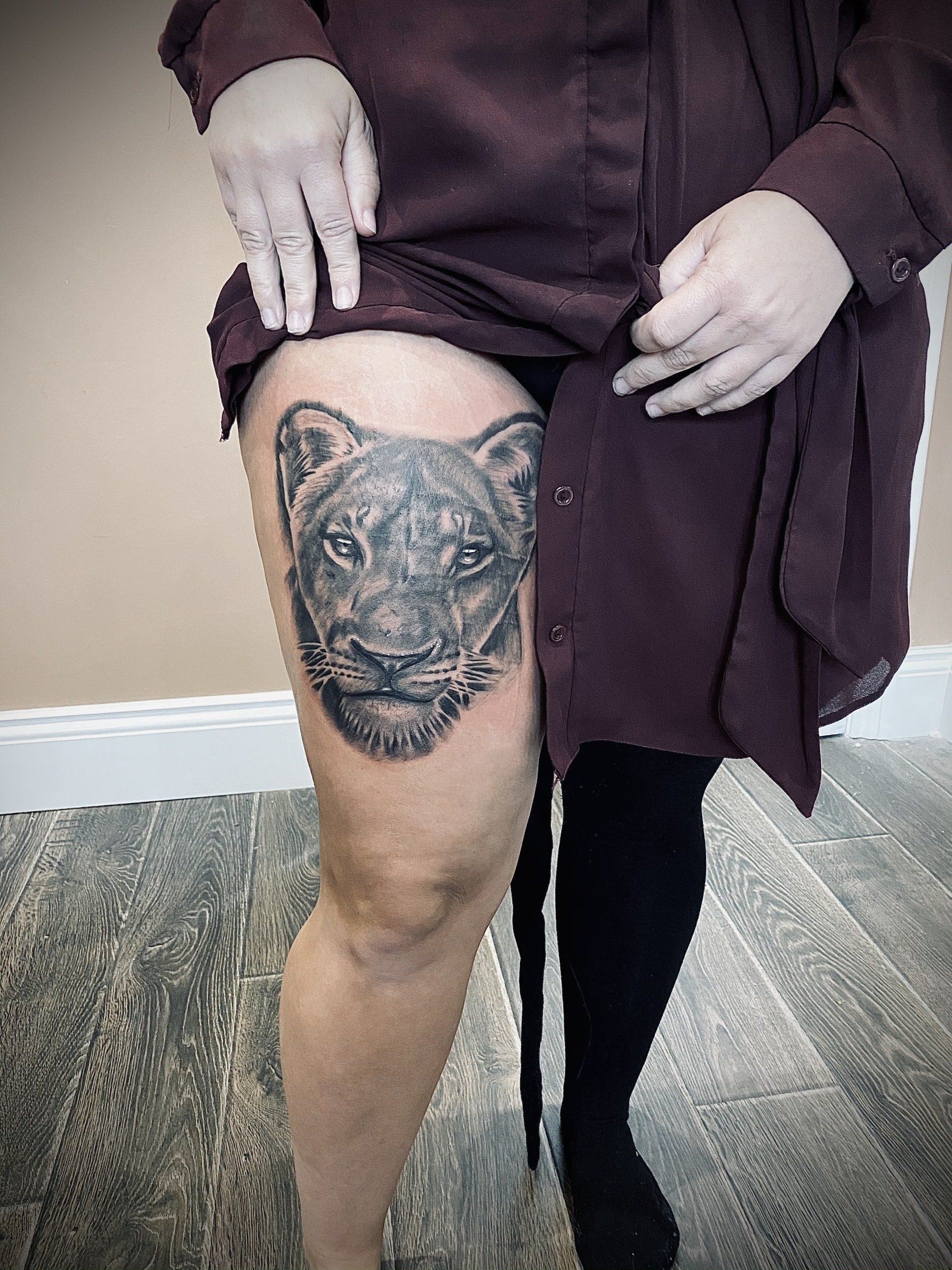 A woman has a tattoo of a lion on her thigh.